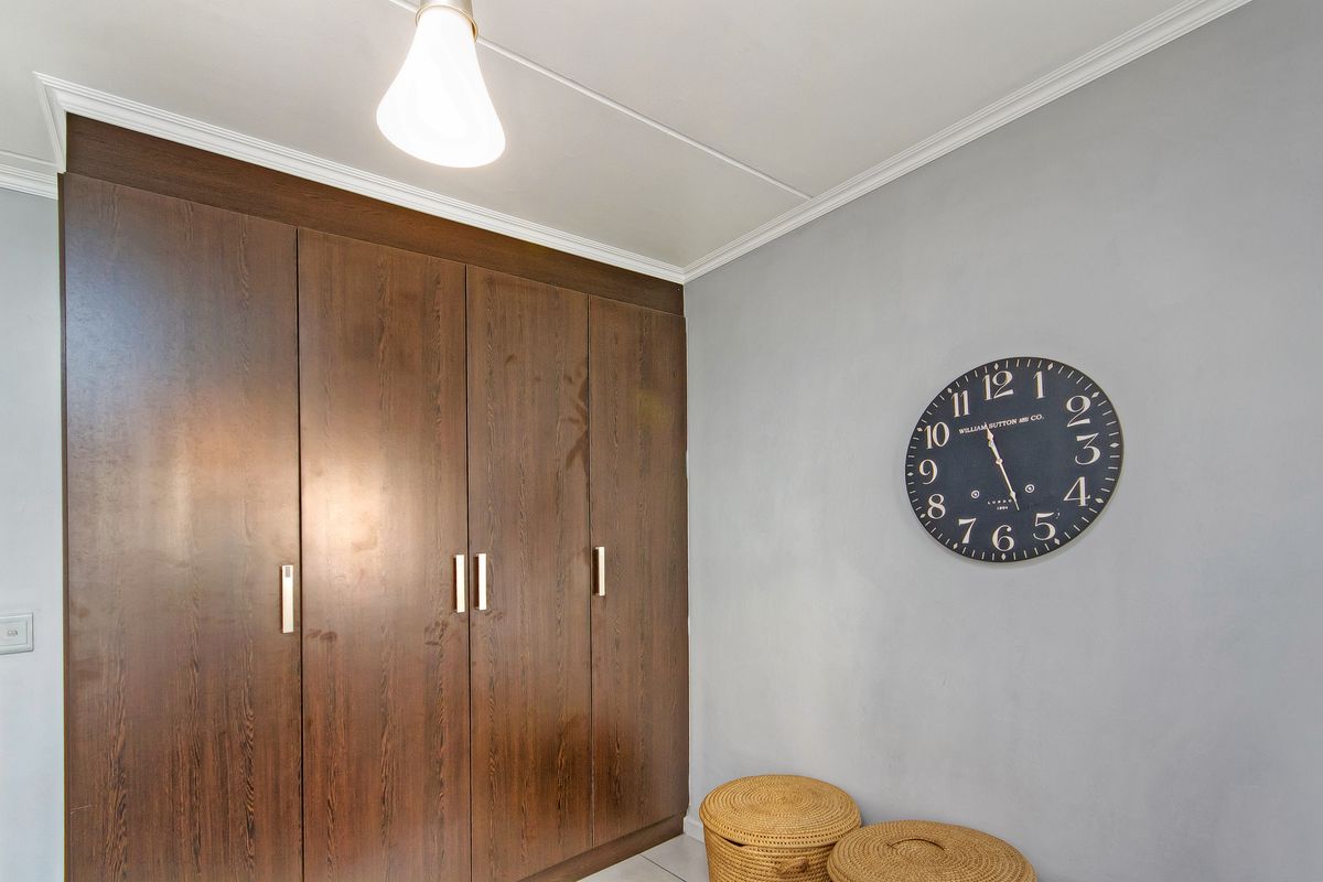 A bedroom featuring dark wood built-in cupboards, crown molding, and neutral grey wall finishes.