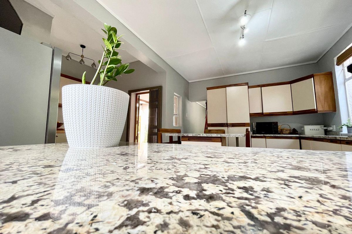A functional kitchen featuring granite countertops, wooden cabinetry, and an open-plan layout that flows into the adjacent living area.
