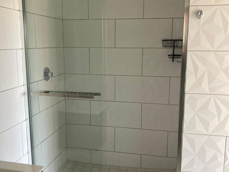 Modern bathroom featuring a spacious walk-in shower with glass enclosure, subway wall tiles, and a stylish textured feature wall.