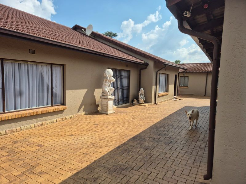 A spacious paved rear courtyard area featuring tiled roofing, security gates, and integrated guttering, providing a functional outdoor space.