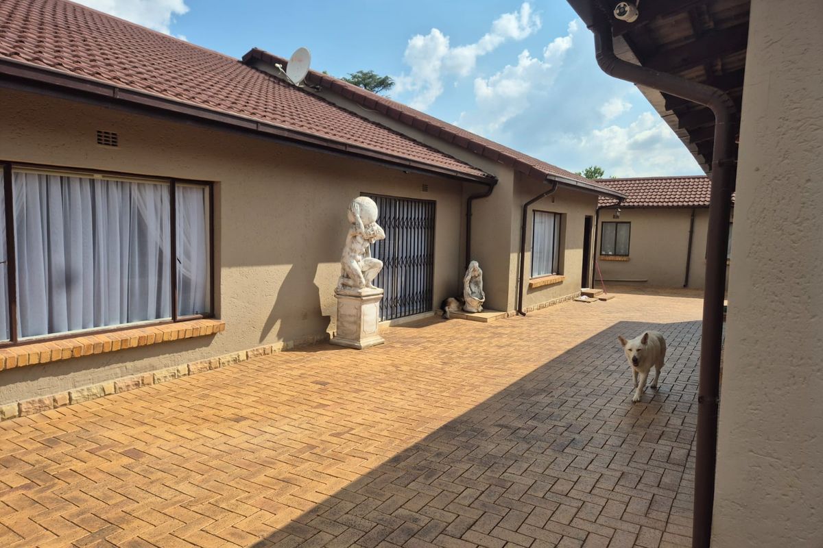A spacious paved rear courtyard area featuring tiled roofing, security gates, and integrated guttering, providing a functional outdoor space.