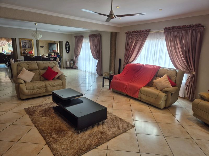 Spacious open-plan living area featuring tiled flooring, recessed lighting, a ceiling fan, and large sliding doors providing ample natural light.