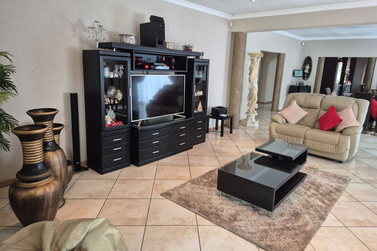 Spacious living room featuring ceramic tiled flooring, decorative columns, and coved cornicing, providing a comfortable and open layout for relaxation.