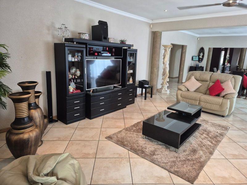 Spacious living room featuring ceramic tiled flooring, decorative columns, and coved cornicing, providing a comfortable and open layout for relaxation.