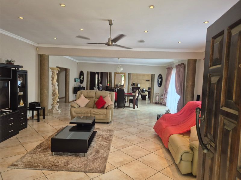 Spacious open-plan living and dining area featuring tiled flooring, decorative columns, and recessed lighting, creating a versatile and connected living space.