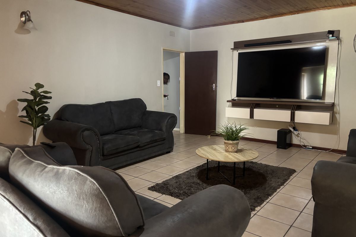 A living room featuring tiled flooring, a timber ceiling, and a built-in media console unit.