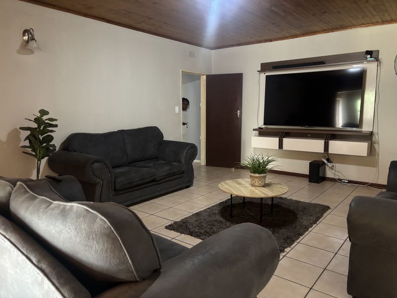 A living room featuring tiled flooring, a timber ceiling, and a built-in media console unit.