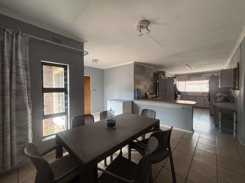 Open plan living and dining area featuring tiled flooring, a breakfast bar, and an adjoining kitchen space with built-in cabinetry.