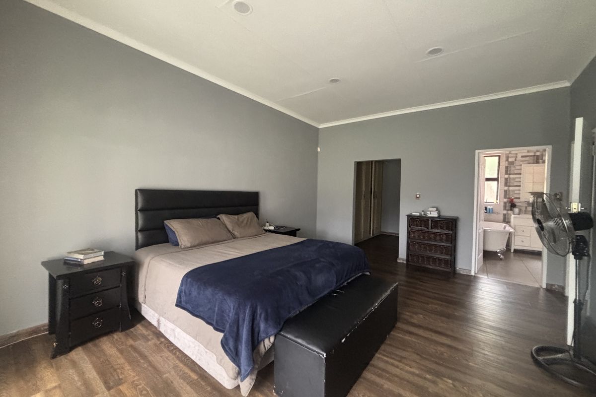 Spacious bedroom featuring laminate flooring, recessed lighting, and an en-suite bathroom access with built-in cupboard storage.