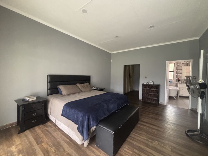 Spacious bedroom featuring laminate flooring, recessed lighting, and an en-suite bathroom access with built-in cupboard storage.
