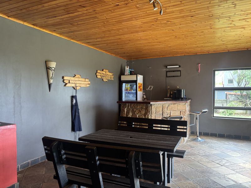 A dedicated bar area featuring a stone-clad counter, timber-clad ceiling, and tiled flooring, providing a functional space for entertainment.