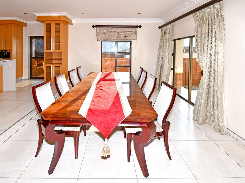 Open plan dining area featuring tiled flooring, coved cornicing, and sliding glass doors leading to the exterior, adjacent to a fitted kitchen.