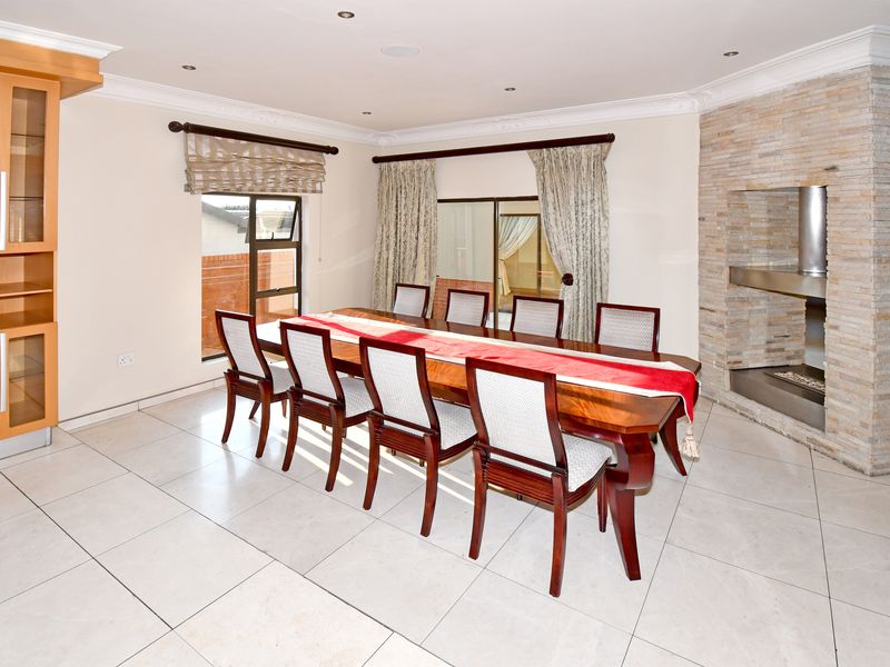 Spacious dining room featuring tiled flooring, a prominent stone-clad fireplace, and built-in cabinetry, offering a well-maintained and functional space for formal entertaining.