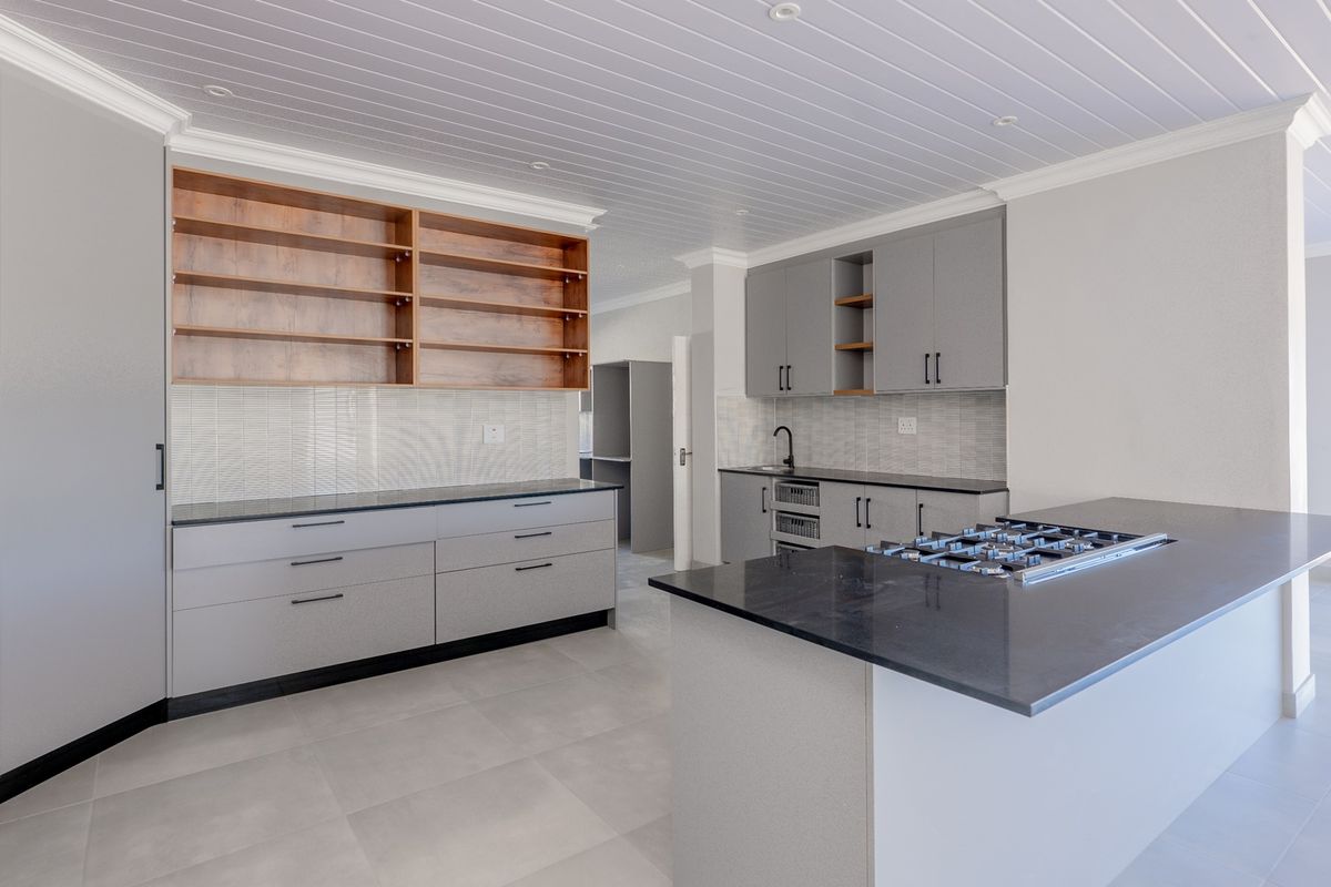 Modern kitchen featuring sleek grey cabinetry, stone countertops, a central island with a gas hob, and elegant tongue and groove ceiling detailing.