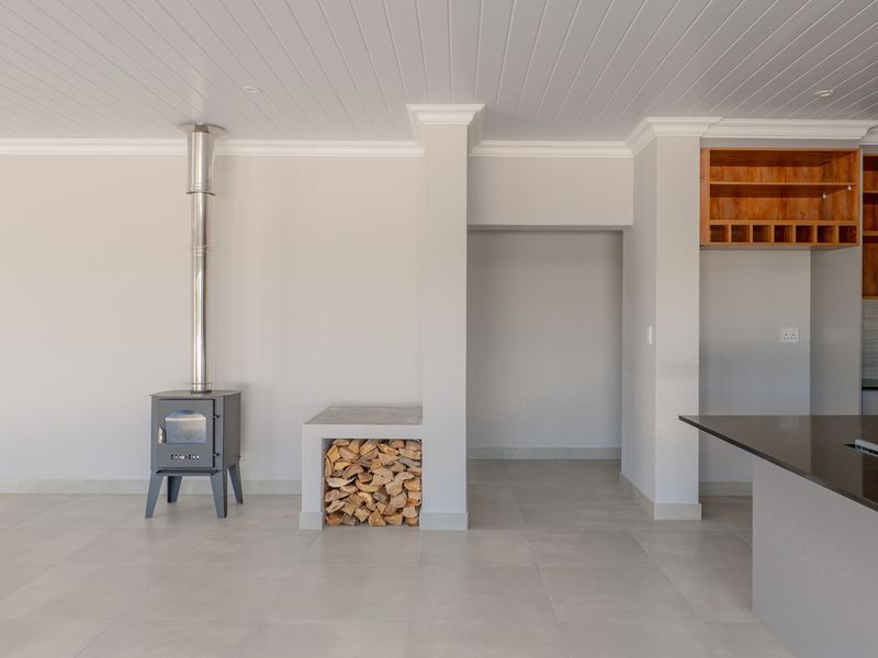 Spacious open-plan living area featuring a modern wood-burning stove, built-in log storage, and a contemporary kitchen with granite countertops and timber cabinetry.