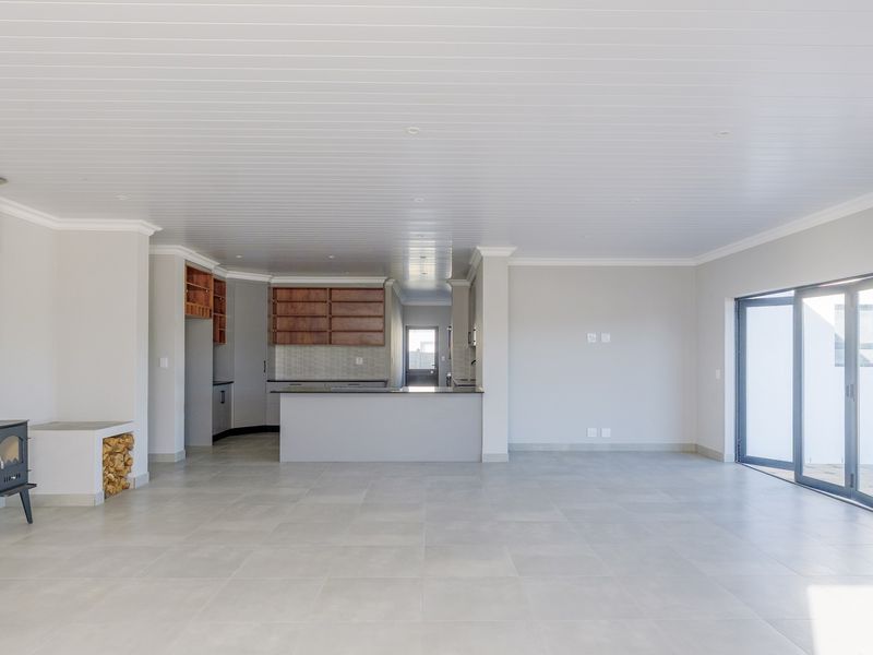 Spacious open-plan living area featuring a modern kitchen, tiled floors, a wood-burning fireplace, and large sliding doors leading to the exterior.