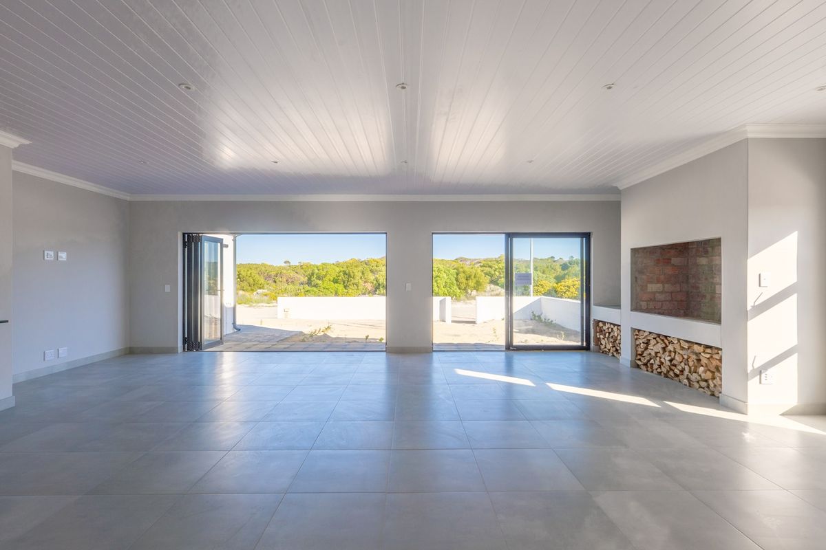 Spacious open-plan living area featuring large bi-fold doors, tiled flooring, and a built-in fireplace with integrated wood storage.