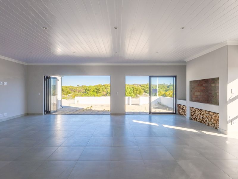Spacious open-plan living area featuring large bi-fold doors, tiled flooring, and a built-in fireplace with integrated wood storage.