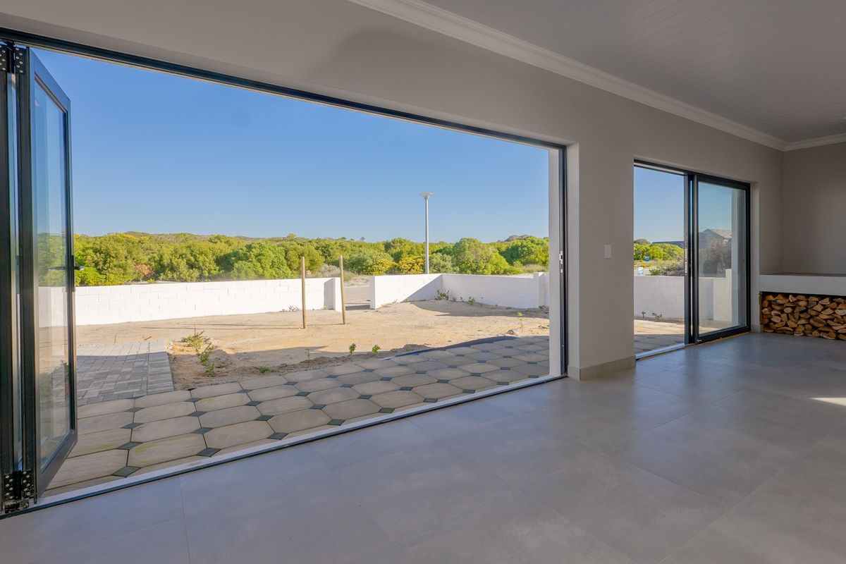 Spacious living area featuring large bi-fold doors opening to a patio, tiled floors, and a built-in fireplace, offering seamless indoor-outdoor flow.