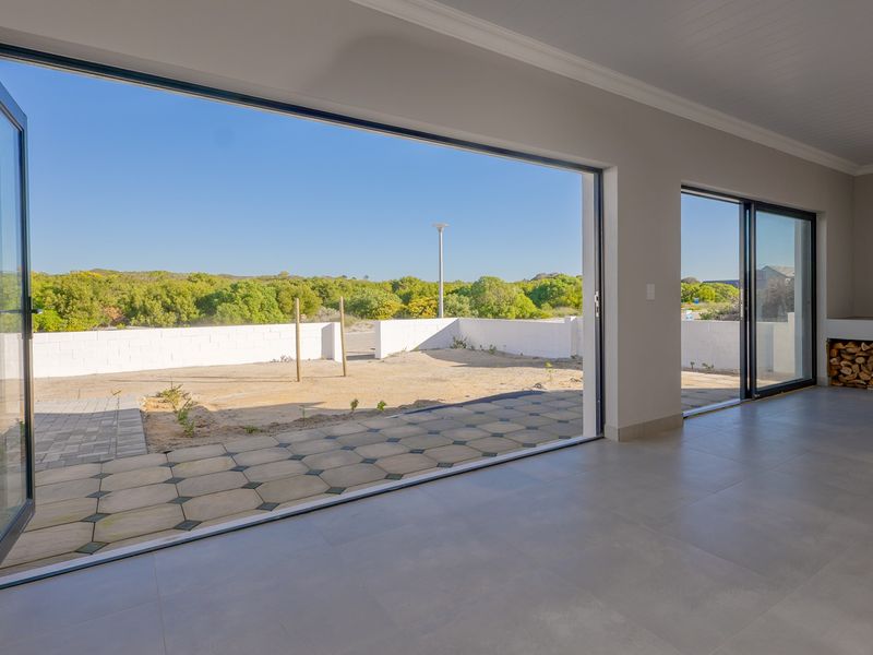 Spacious living area featuring large bi-fold doors opening to a patio, tiled floors, and a built-in fireplace, offering seamless indoor-outdoor flow.