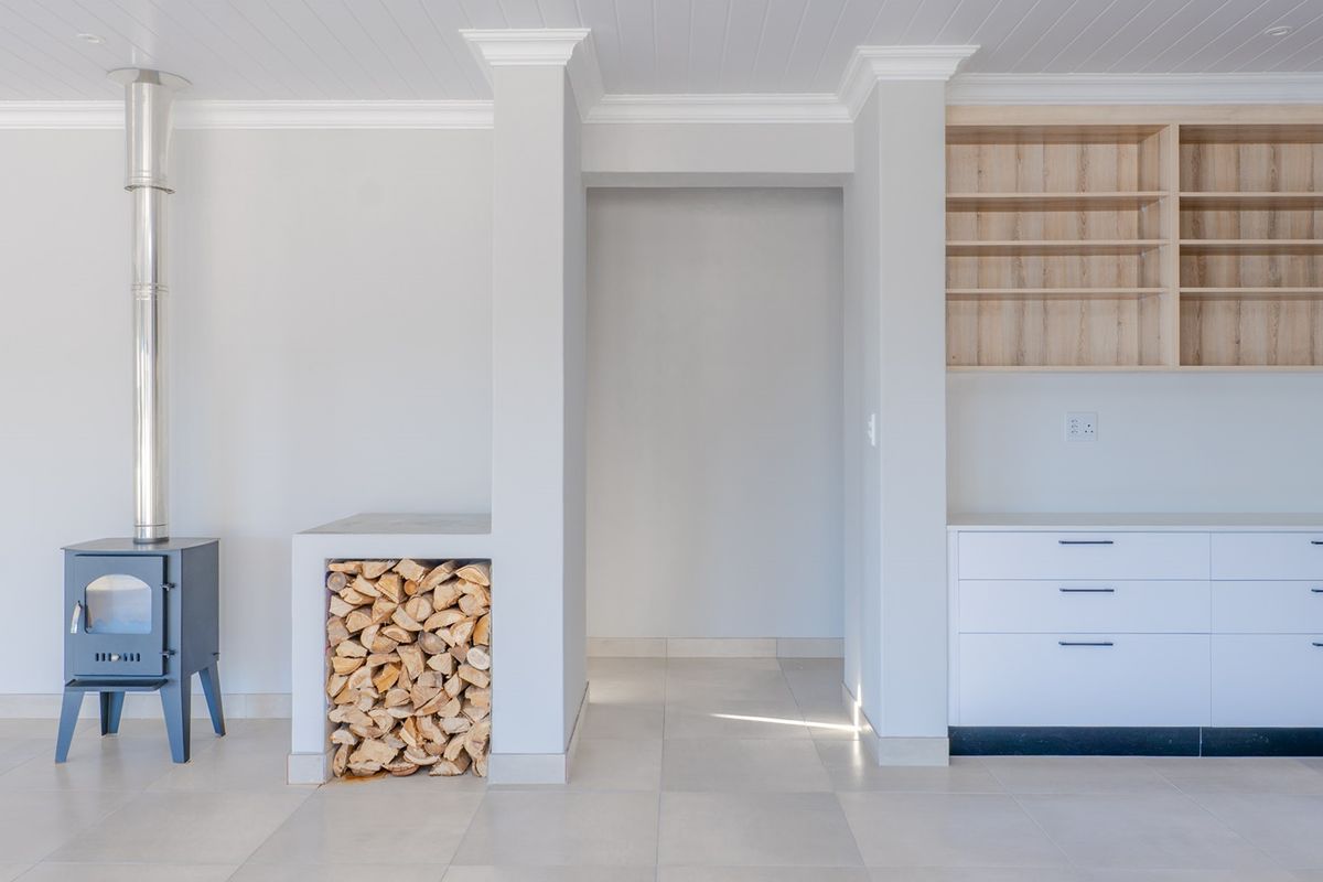 Bright living area featuring a modern wood-burning fireplace, integrated firewood storage, and clean built-in cabinetry with open shelving.