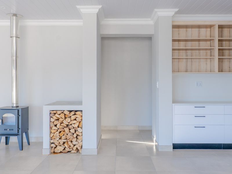 Bright living area featuring a modern wood-burning fireplace, integrated firewood storage, and clean built-in cabinetry with open shelving.