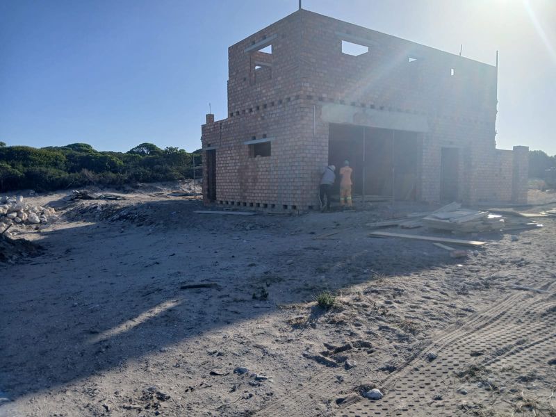 A construction site showing the exterior brick shell of a house currently under development.