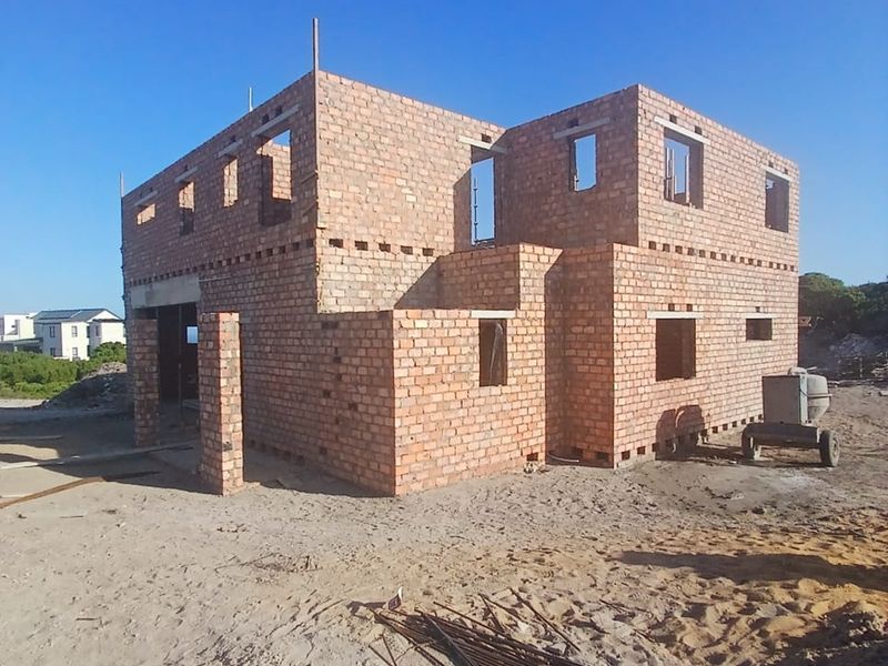 A double-story residential property currently under construction, featuring exposed brickwork and structural masonry walls in the early stages of development.
