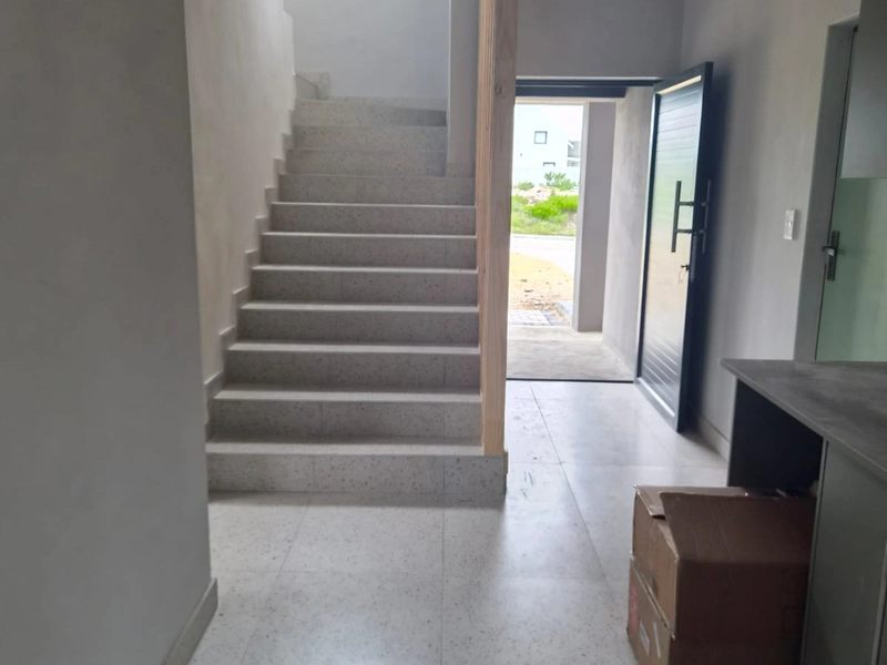 Entrance hall featuring terrazzo flooring and staircase, timber support column, and direct access to the exterior.