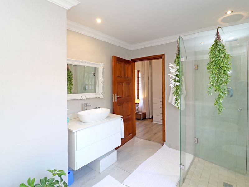Modern bathroom featuring a sleek vanity with vessel sink, glass-enclosed shower, and neutral finishes, offering a clean and contemporary aesthetic.