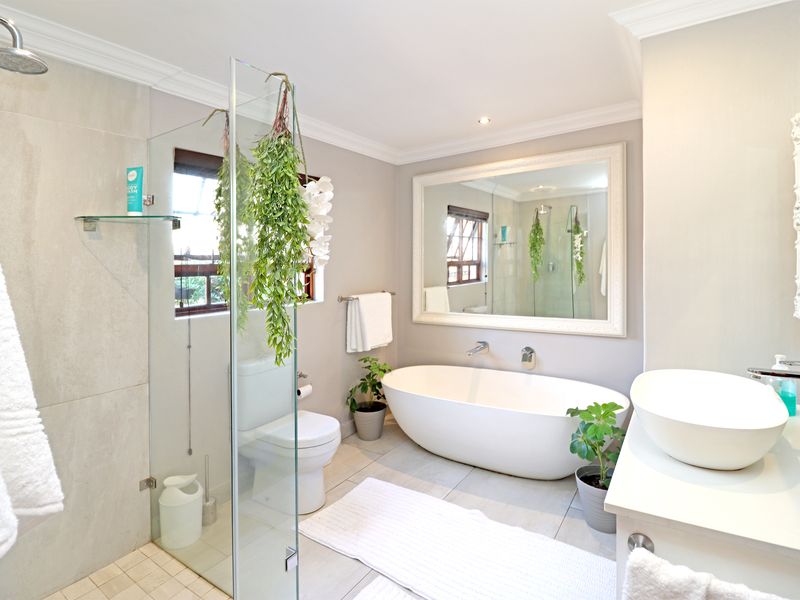Modern bathroom featuring a freestanding bathtub, glass-enclosed shower, vessel sink vanity, and large wall mirror with neutral tiled finishes.
