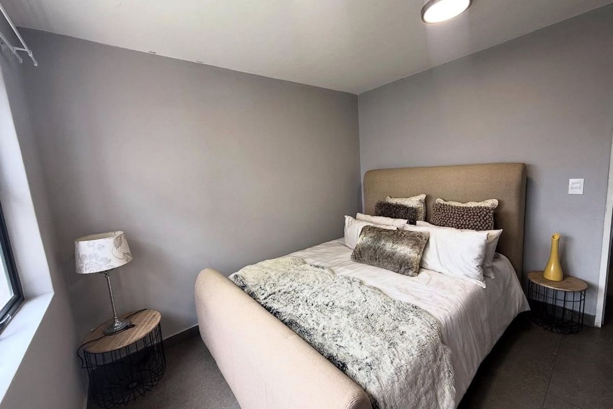 A well-maintained bedroom featuring neutral grey walls, tiled flooring, and a modern flush-mount ceiling light fixture.