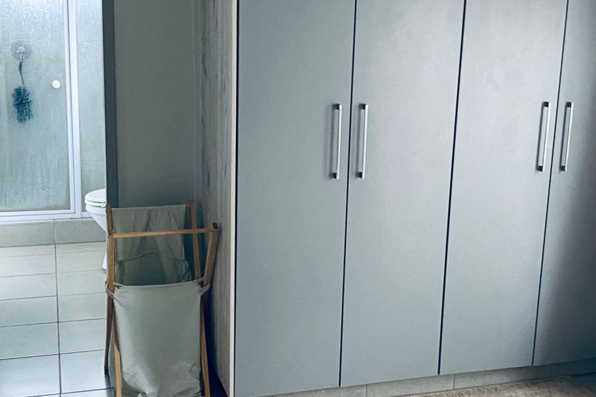Bedroom featuring built-in wardrobes with a neutral finish and tiled flooring, with an adjacent en-suite bathroom visible.
