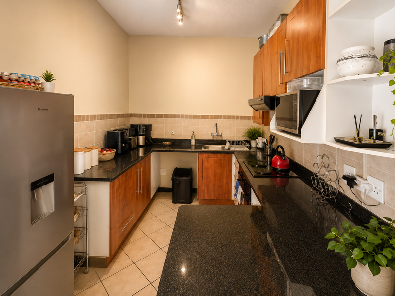 A functional kitchen featuring granite countertops, wooden cabinetry, ceramic tile backsplash, and integrated appliances, offering a practical layout for daily use.
