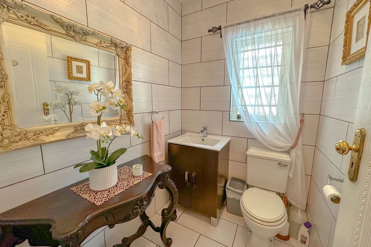A compact guest bathroom featuring floor-to-ceiling wall tiles, a modern vanity with integrated basin, and a standard toilet.
