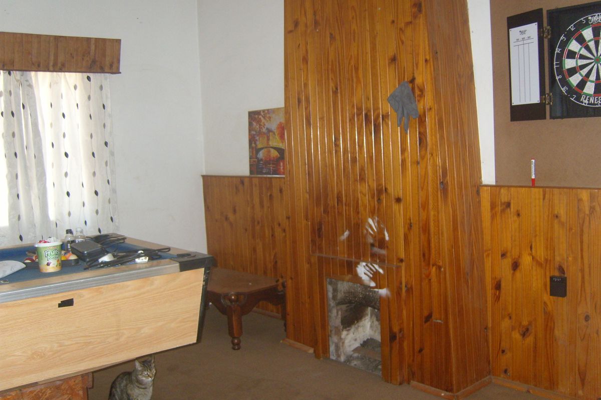 Living room featuring dated timber wall paneling and a built-in fireplace, offering potential for a modern renovation to update the interior aesthetic.