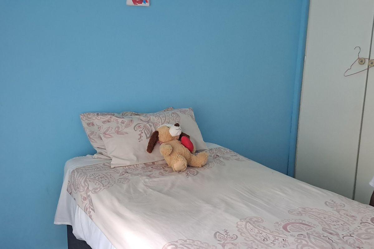 A bedroom featuring a built-in wardrobe with white doors and blue painted walls.