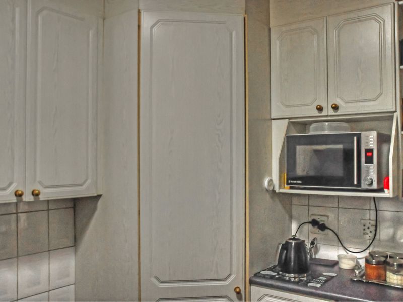 A functional kitchen area featuring traditional cabinetry, a tiled backsplash, and a dedicated built-in microwave shelf.