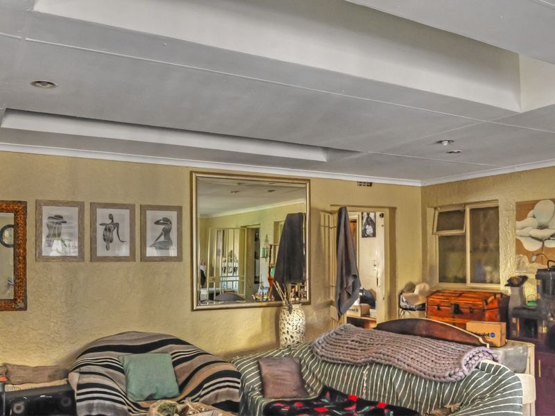 A living room featuring a recessed ceiling with downlights and textured wall finishes, offering a functional space for relaxation.