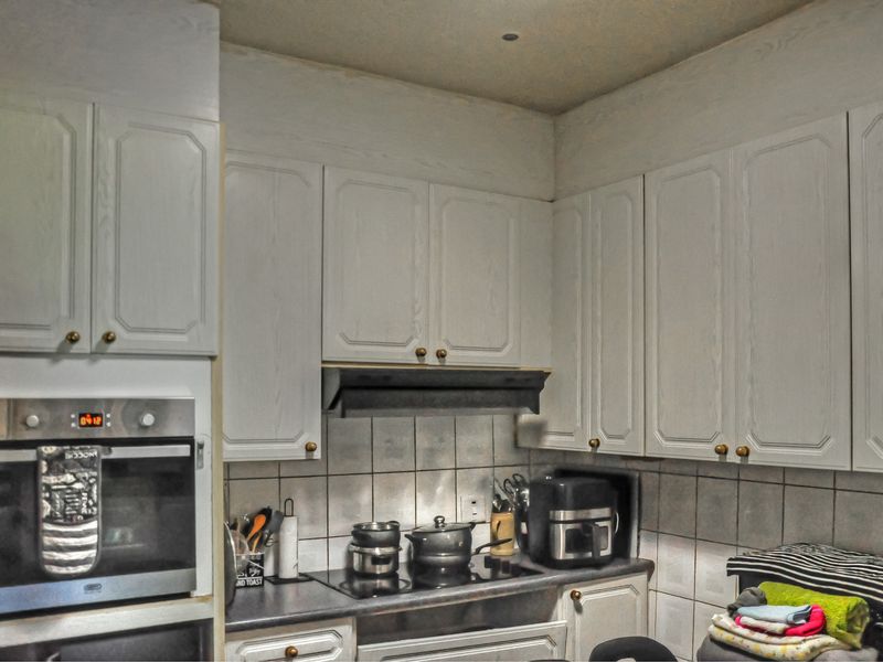 A functional kitchen featuring built-in oven, electric cooktop, extractor fan, and ample cabinetry with a tiled backsplash.