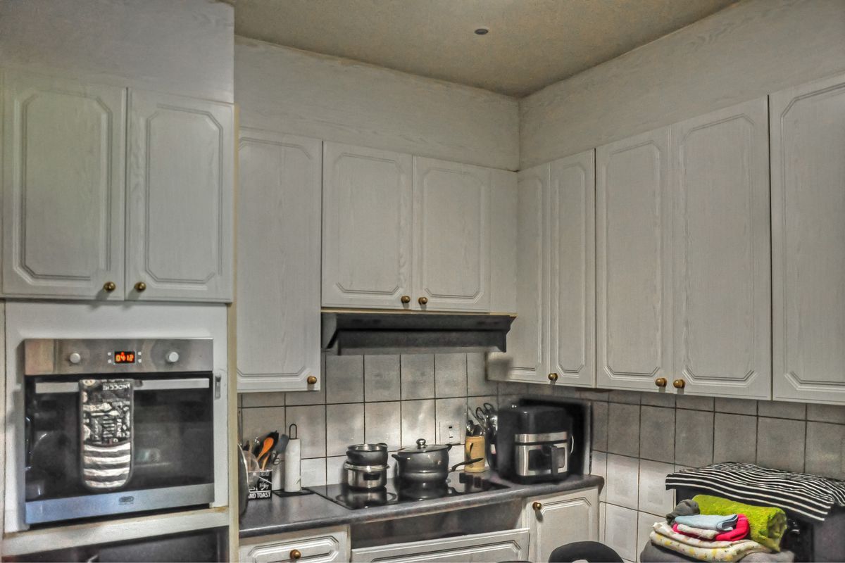 A functional kitchen featuring built-in oven, electric cooktop, extractor fan, and ample cabinetry with a tiled backsplash.