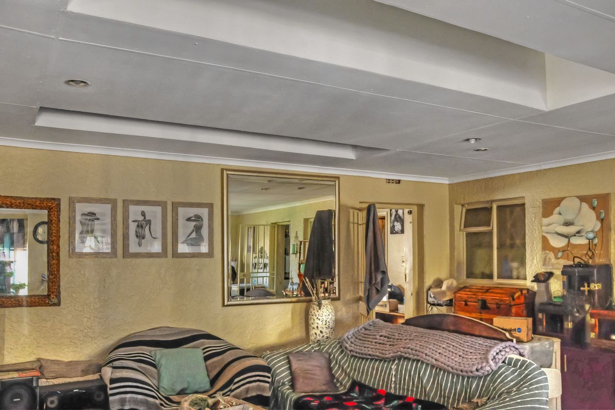 A living room featuring a recessed ceiling with downlights and textured wall finishes, offering a functional space for relaxation.