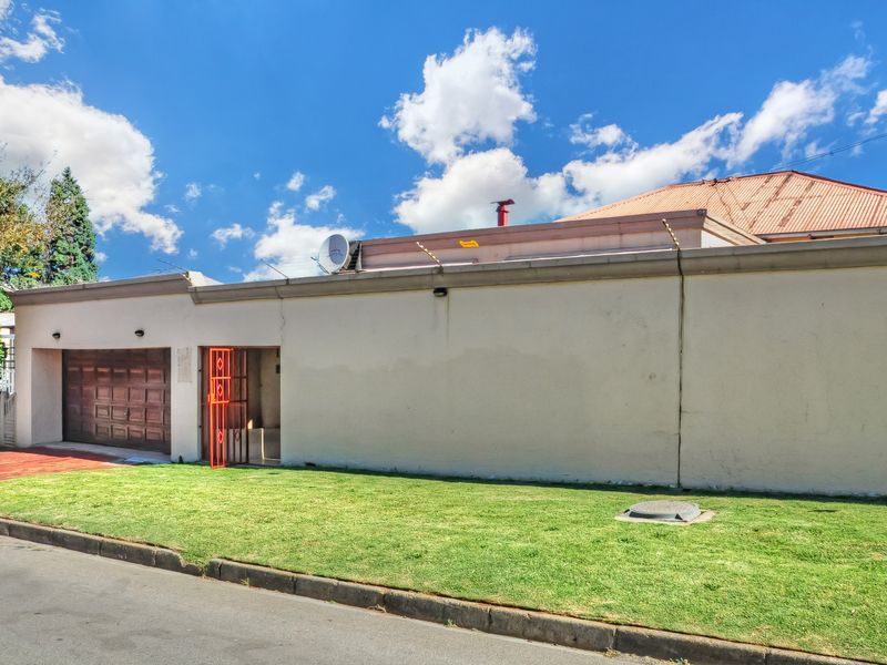 Front exterior view of the property featuring a garage, security gate, and perimeter wall with electric fencing.