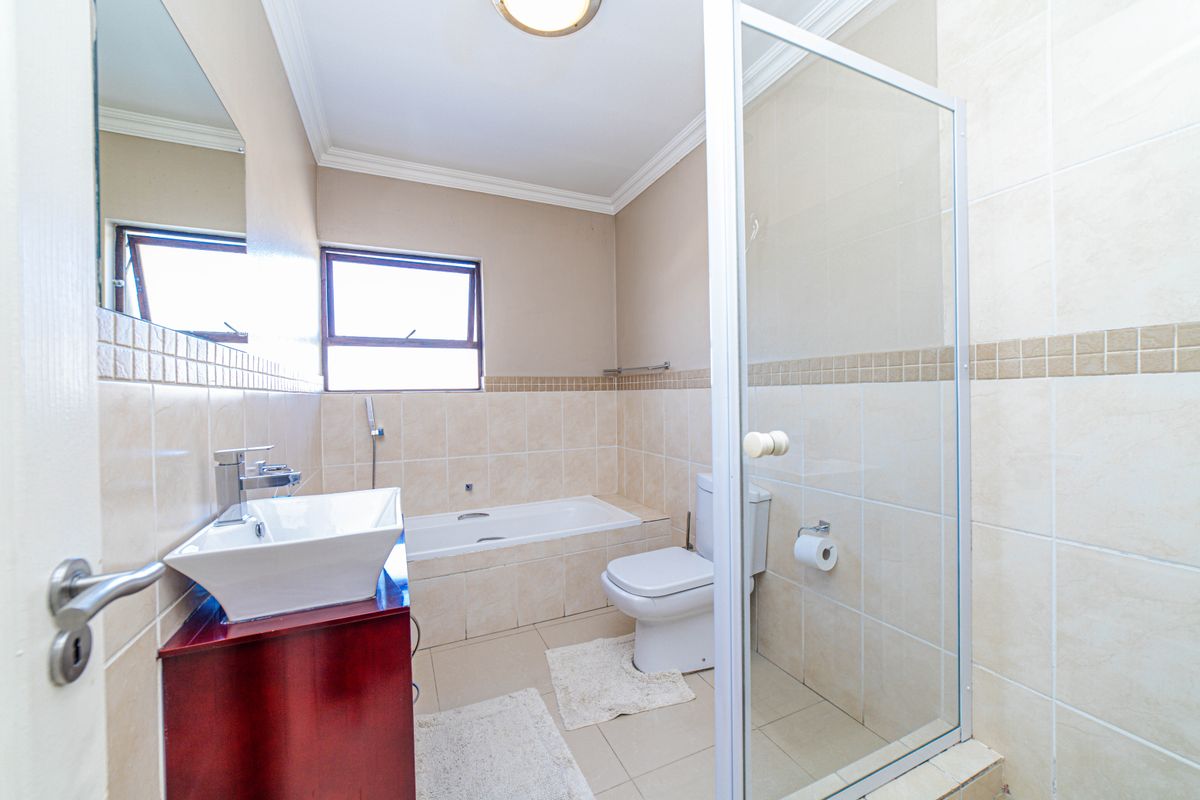 A functional bathroom featuring a tiled bathtub, a separate glass-enclosed shower, a modern vessel sink vanity, and a standard toilet.