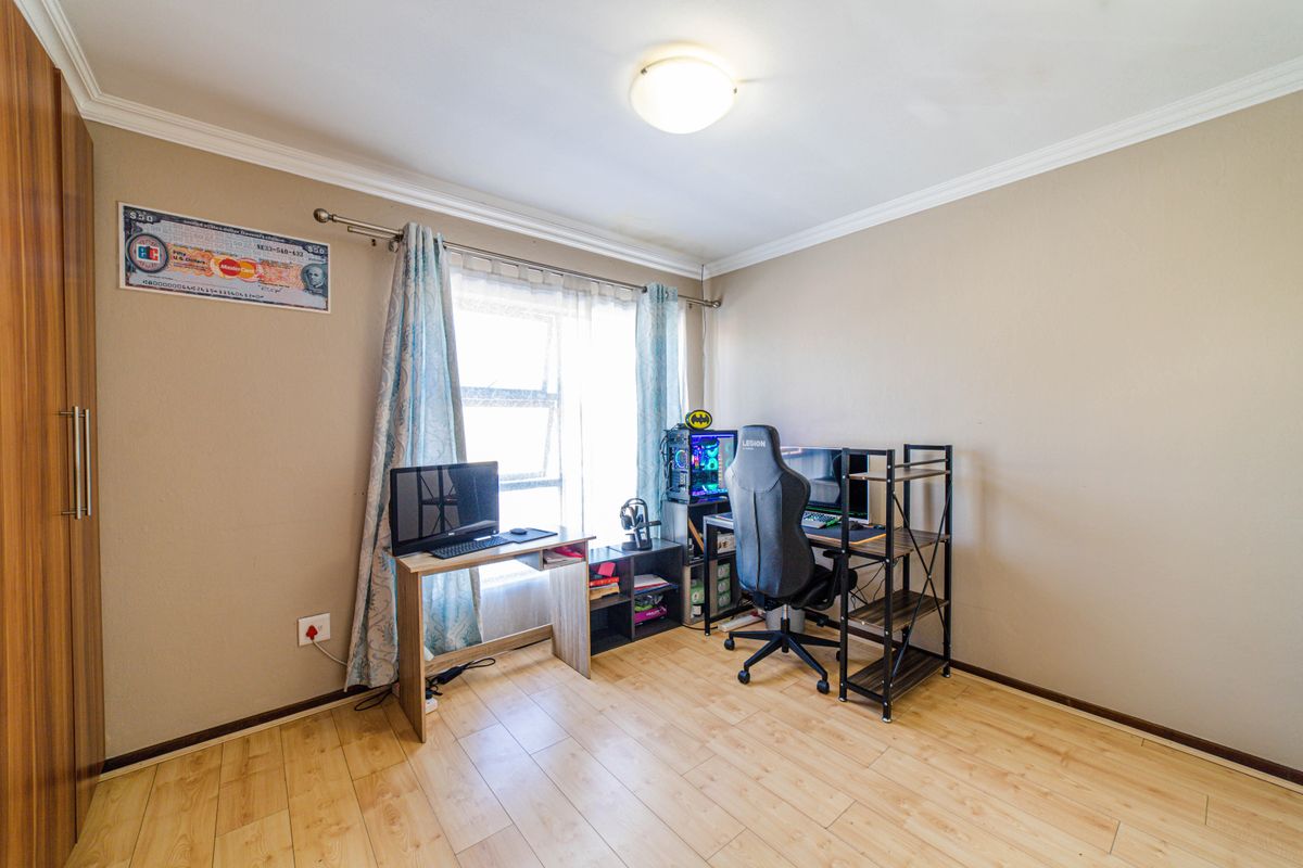 A bedroom featuring light wood-look laminate flooring, built-in cupboards, and a window with curtain rods.