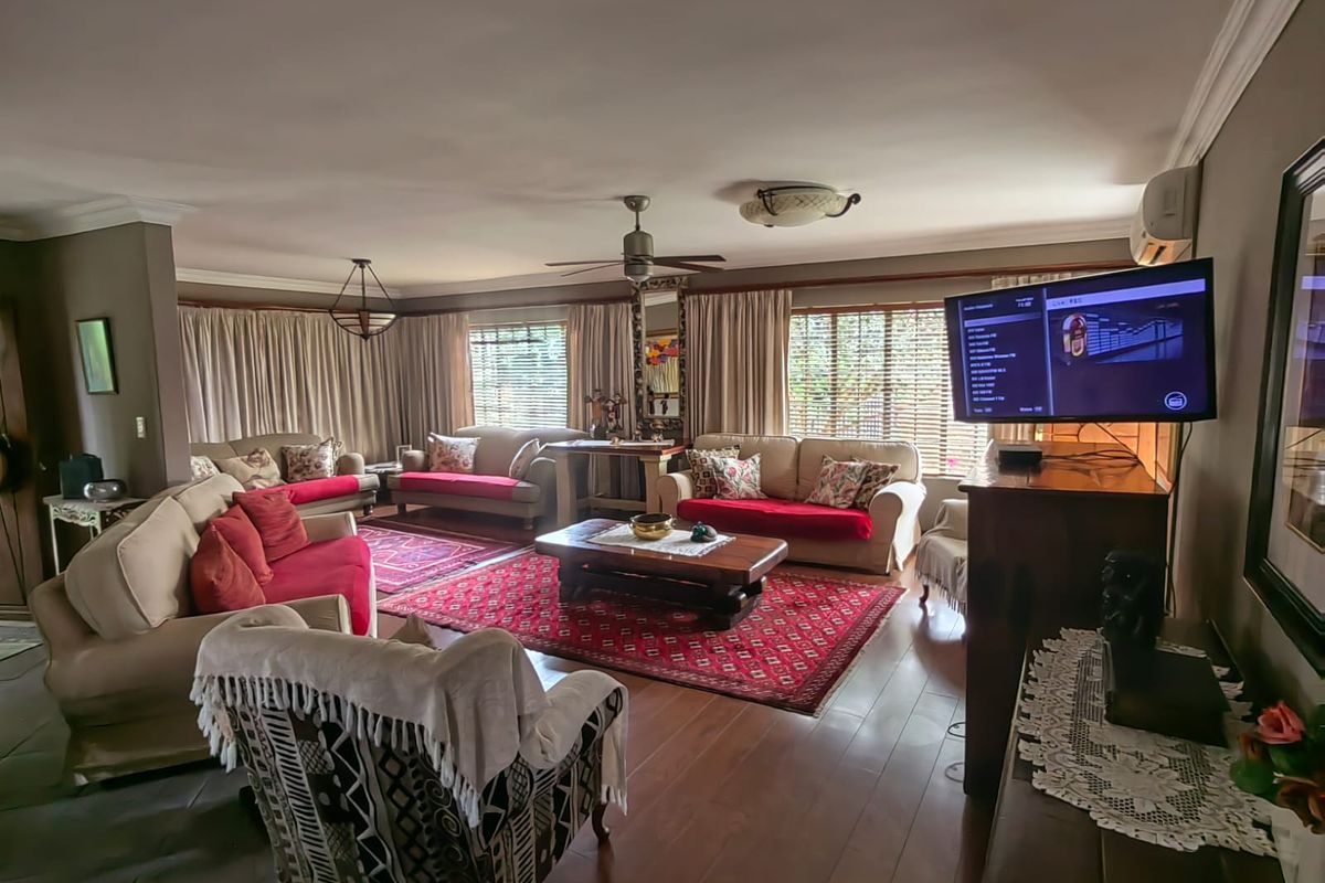 Spacious living room featuring laminate flooring, a ceiling fan, and wall-mounted air conditioning, offering a comfortable and functional layout for relaxation.