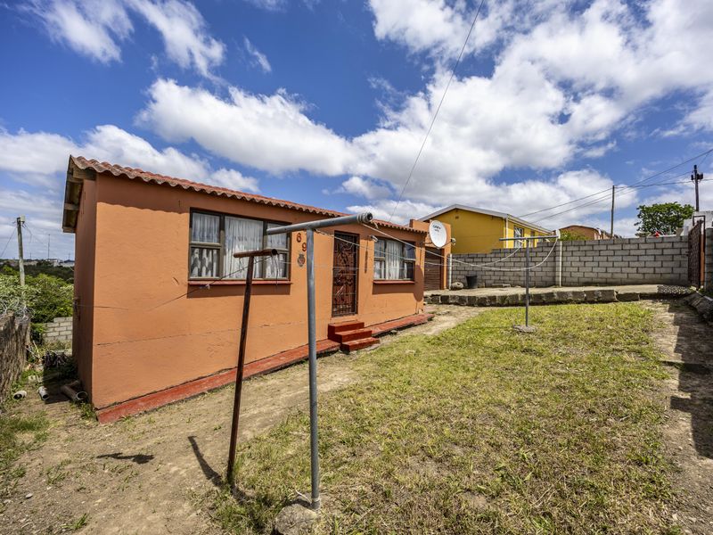 Rear view of the property featuring a small garden area, concrete block boundary walls, and exterior access with security gate.