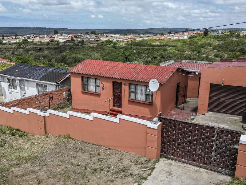 Aerial view of a residential property featuring a corrugated metal roof, perimeter wall, and attached garage in a suburban setting.