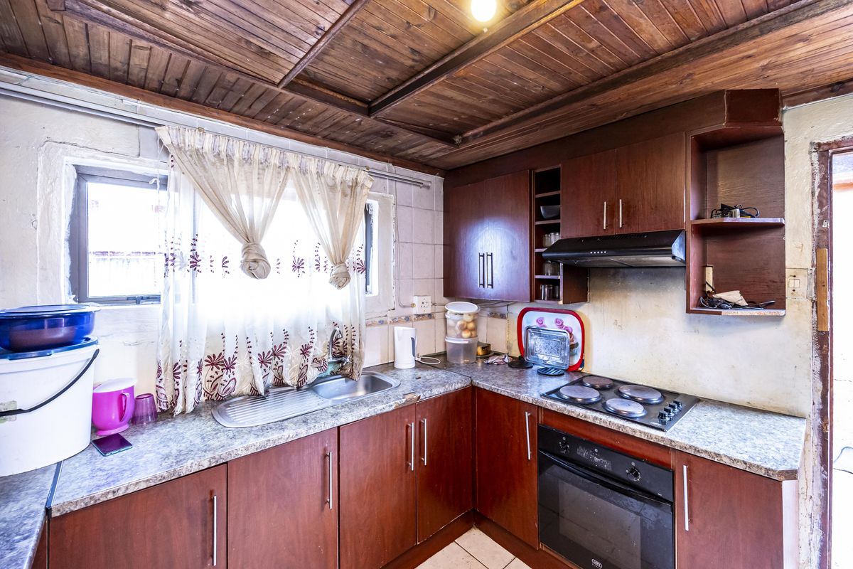 A dated kitchen featuring timber panelled ceilings, built-in wooden cabinetry, laminate countertops, and integrated cooking appliances.