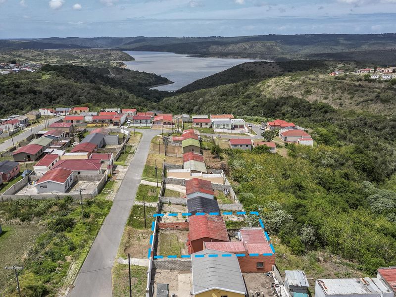 Aerial view of a residential property in a suburban estate, highlighting the building footprint, boundary walls, and surrounding landscape with distant water views.